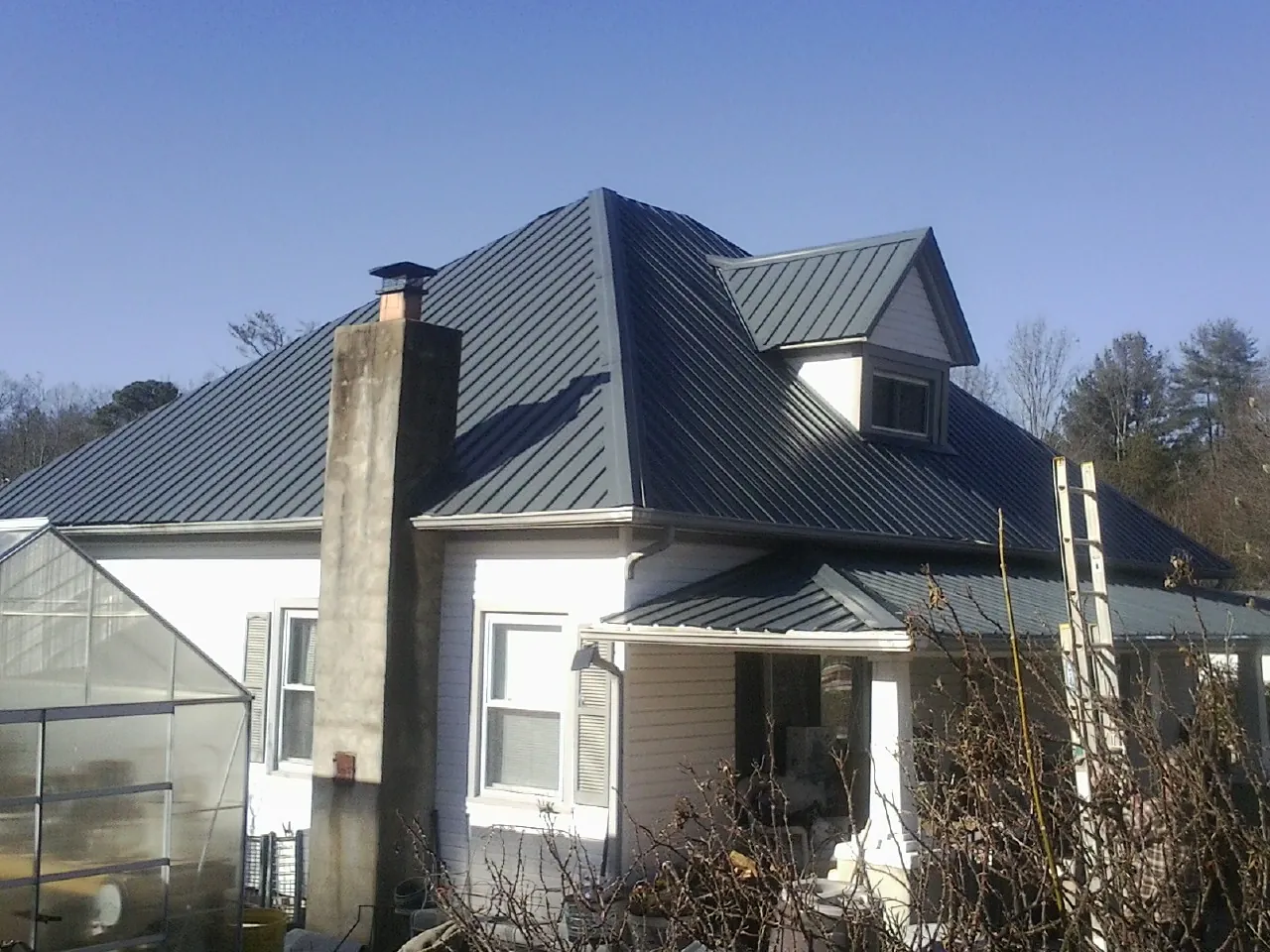 Dark blue standing seam metal roof on a white farmhouse with dormer — Slate & Tile Roof Repair by Roofing Brothers in Wampum