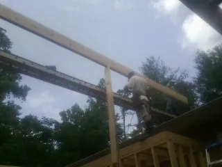 Carpenter setting a ridge beam over a new addition frame — Ice Dam Removal by Roofing Brothers in Wampum