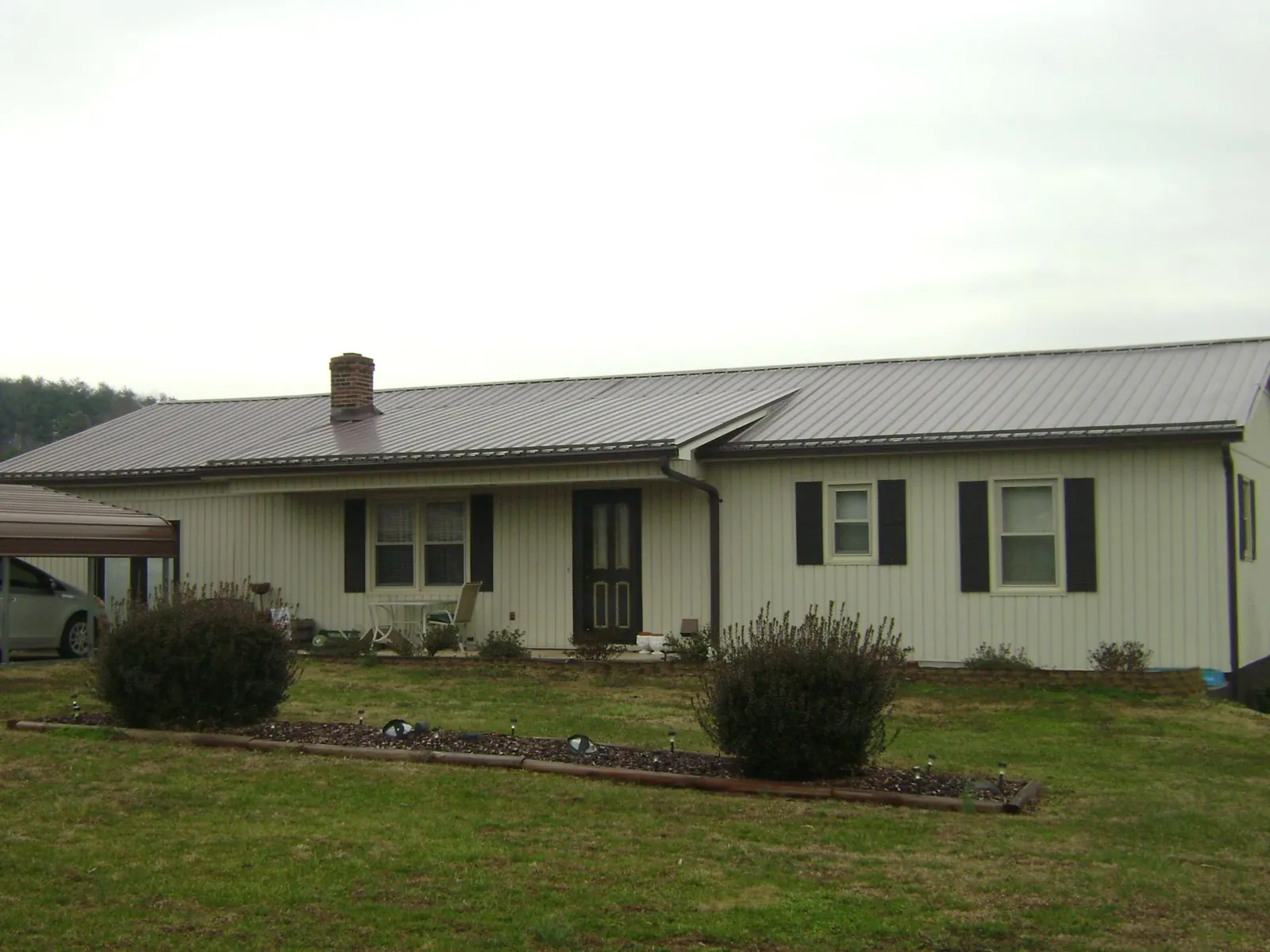 Brown metal roof on a cream sided ranch home with a brick chimney in Wampum