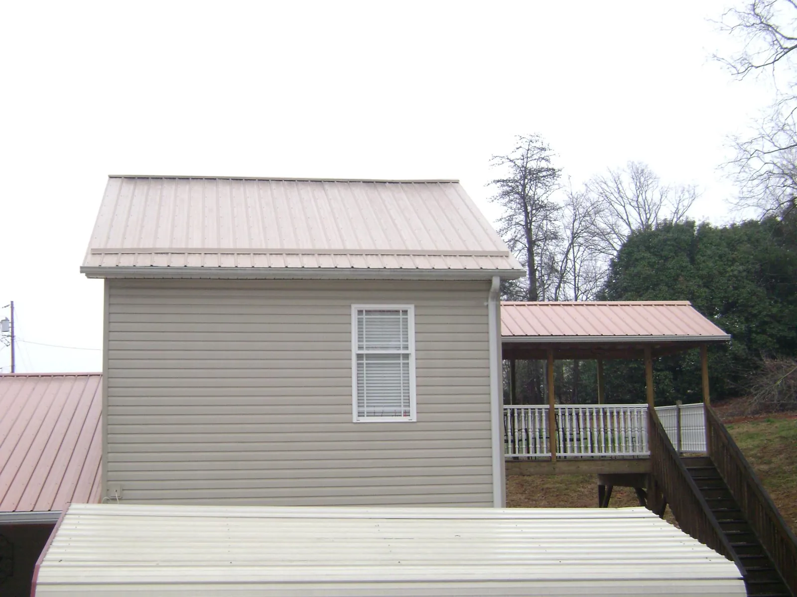 Tan metal roofs on a two story addition and attached porch, from a Roof Replacement job in Wampum