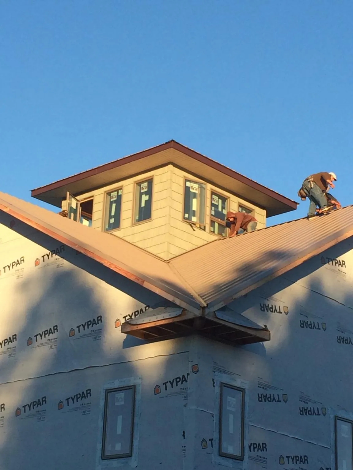 Roofers working around a rooftop cupola on a new metal roof at sunset — Roof Waterproofing in Wampum by Roofing Brothers